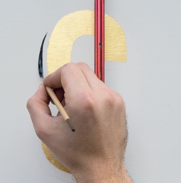 A hand painting a golden shape
